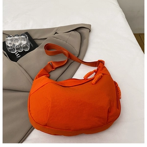 Detail of orange nylon hobo bag featuring wide strap and unique rope zipper puller