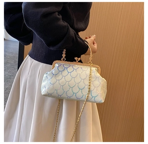 Detail of white sequin handbag with gold metal handle and chain strap on a model