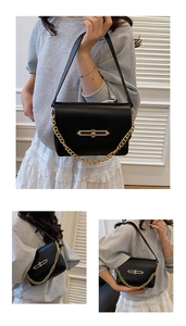 Détail d'un sac en cuir noir avec un fermoir doré élégant et une chaîne métallique décorative