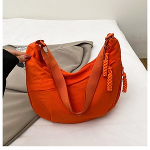 Detailed macro view of bright orange nylon crescent bag with woven rope zipper pulls
