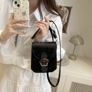 Mini black velvet crossbody bag with wooden buckle shown in a mirror selfie