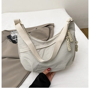 Detail of light grey nylon crescent bag with textured fabric and braided rope accents