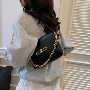 Petit sac carré en cuir noir avec chaîne dorée épaisse porté par une femme
