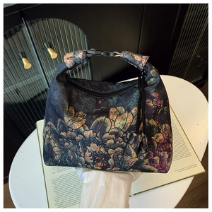 Detailed view of vintage floral crescent bag with zipper and buckle on a white table