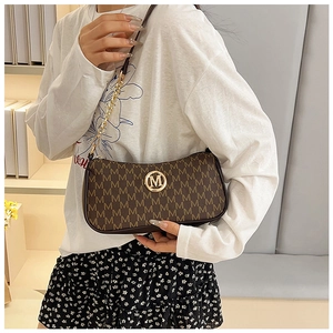 Close-up of monogrammed brown crescent bag with gold M logo and leather chain strap