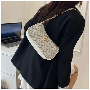 Close-up of beige crescent underarm bag with letter prints and gold chain strap