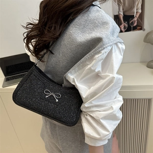 Sac baguette noir scintillant à la mode avec nœud en métal argenté porté à l'épaule