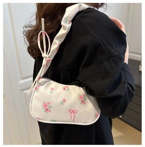 Détail du sac blanc sous l'aisselle avec roses roses, nœuds et bandoulière à volants