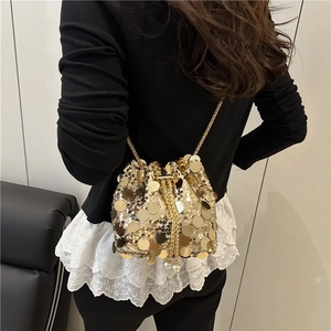 Elegant gold sequin bucket bag with chain strap styled on a model in a minimalist setting