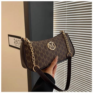 Close-up of crescent underarm bag with vintage M pattern print and gold logo detail