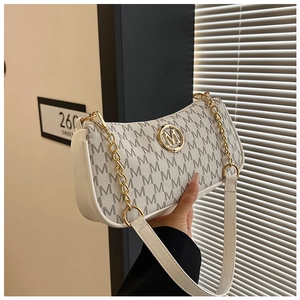 Detail showing creamy white moon bag with gold emblem and monogram pattern finish