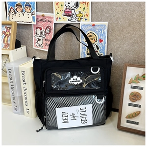 Detail view of the black canvas tote bag showing transparent window and mesh pocket detail
