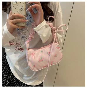 Détails du sac sous le bras rose avec motifs de roses et détails de nœuds
