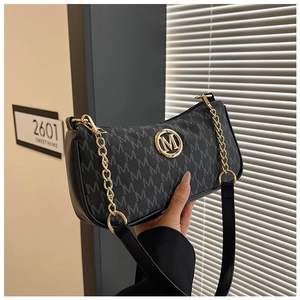 Detail of the golden M logo on a black crescent bag with monogram printing