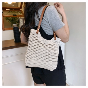 Dettaglio della borsa tote in paglia intrecciata con spalline in pelle e rivetti in metallo
