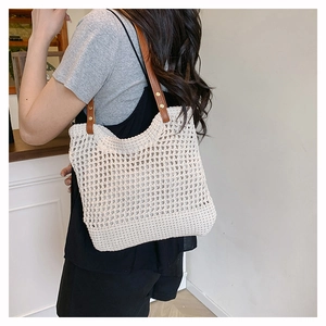 Dettaglio della borsa tote all'uncinetto beige con manici in finta pelle marrone e rivetti