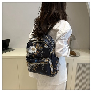 Detail of floral print backpack with white daisies on black fabric for women