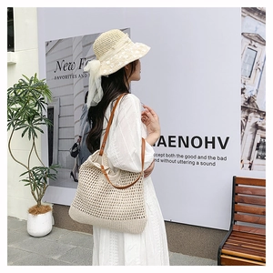 Dettaglio della borsa tote intrecciata beige con tracolla in pelle indossata da una modella