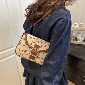 Chic cherry print shoulder bag in cream canvas with brown straps and metal buckle closure