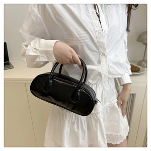Detailansicht einer schwarzen Baguette-Tasche aus Lackleder mit elegantem Metallreißverschluss