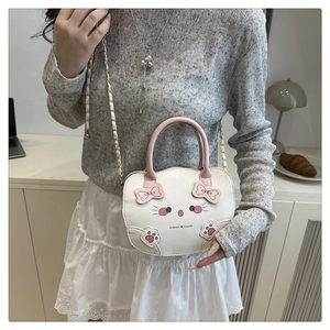 Detalle del bolso bandolera de gato blanco con lazo rosa y correa de cadena dorada