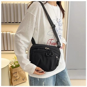 Detail of black nylon crossbody bag with multiple zipper compartments and adjustable strap