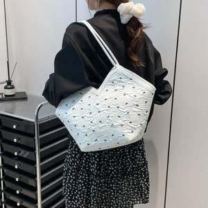 White bucket tote bag with black bow patterns and slim handles for minimalist daily wear