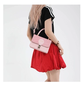 Detail showing the pink crossbody bag with woven texture flap and golden metal clasp closure
