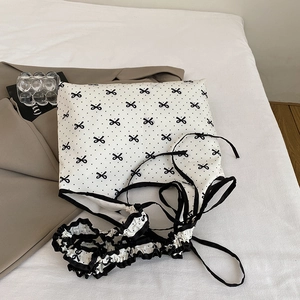 Detail showing white chiffon fabric with black polka dots, bow print and ruffled edges