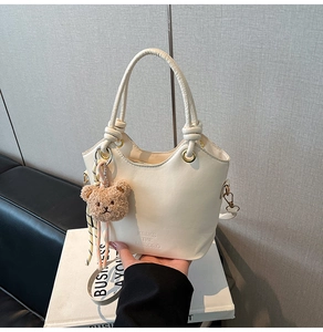 Détail du sac seau blanc en similicuir avec logo et breloque ours en peluche marron