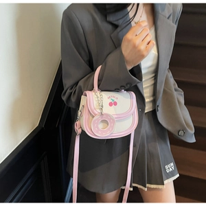 Close-up of a pink contrast flap bag featuring cherry print and a cute donut charm