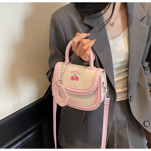 Detail of a pink and beige cherry print handbag with logo and ring charm accessory