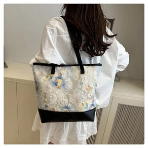 Sac fourre-tout à fleurs porté par un mannequin dans une pièce épurée, grand volume et cuir