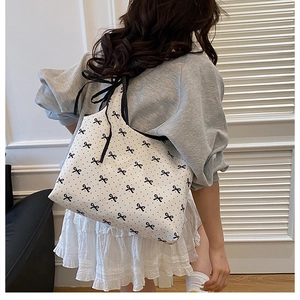 Polka dot canvas tote bag with black ribbon bows shown on shoulder in indoor setting