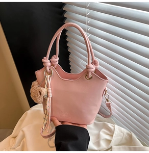 Sac seau rose avec foulard en soie et breloque ours dans une lumière naturelle