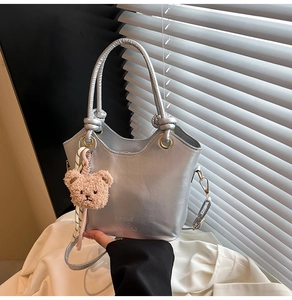 Détail du sac cabas argenté avec poignée à nœud décoratif et charme ours marron