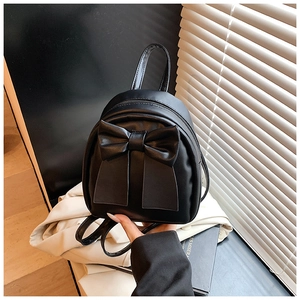 Detail of trendy mini black backpack with stylish bow decoration and matte PU leather texture