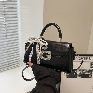 Detail of glossy leather bag with pearl bow, lace ribbon and rhinestone G buckle