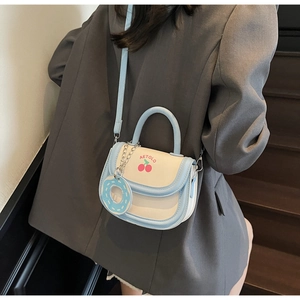 Close-up of a blue and white crossbody bag with cherry prints and a donut charm