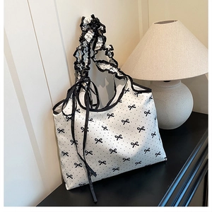 Close-up of a white polka dot tote bag featuring a scrunchie strap and ribbon ties