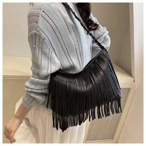 Détail du sac à bandoulière noir à franges montrant la sangle tressée et les pompons