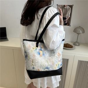 Grand sac cabas artistique avec motif floral et anses en cuir porté par un mannequin