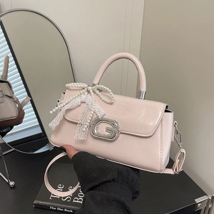 Detail of light pink patent leather handbag with diamond G logo and pearl lace bow