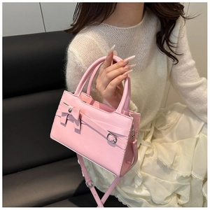 Pink PU leather handbag with bow detail shown on a model in a casual outdoor setting