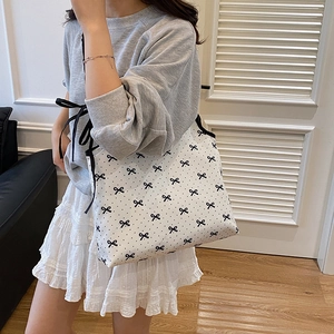 Polka dot canvas tote bag with bow design worn by a model in a minimalist setting
