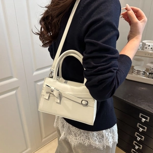 Chic cream-white square handbag with bow accent and detachable strap shown on model