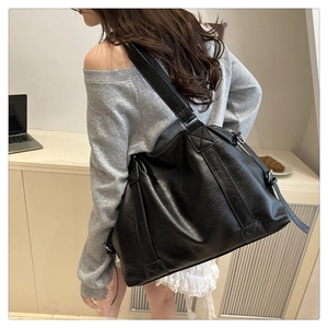 Detailed side view of a large black PU leather tote bag worn by a model in a casual setting