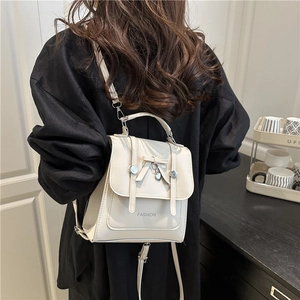 Creamy white butterfly lock multi-purpose backpack and shoulder bag for women worn by model
