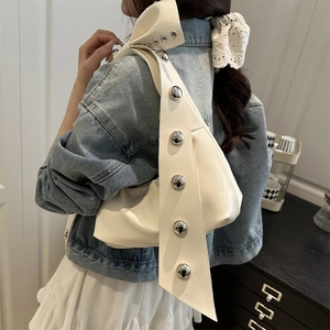 Cream white underarm bag with oversized silver studs and bow-style shoulder strap