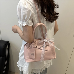 Sac à main vintage rose en forme de coquillage avec nœud en dentelle porté par un mannequin